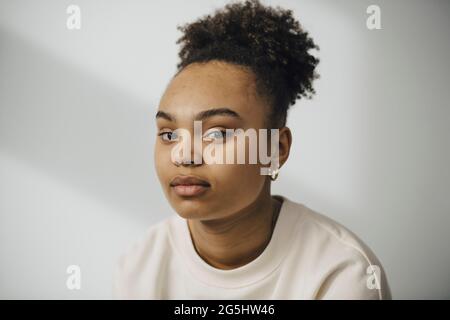 Portrait de jeune femme contre mur blanc Banque D'Images