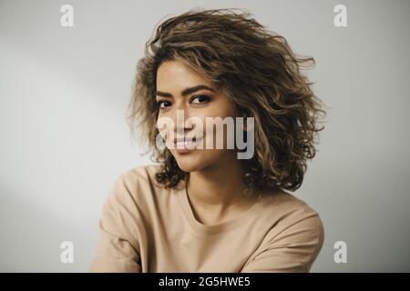 Portrait d'une femme souriante avec des cheveux bruns sur fond blanc Banque D'Images