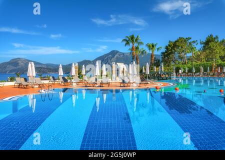 Belle piscine avec chaises longues et parasols au lever du soleil Banque D'Images