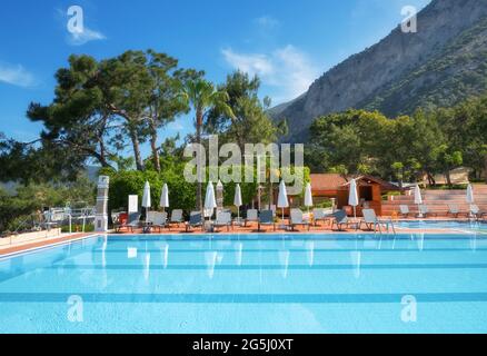 Belle piscine avec chaises longues et parasols au lever du soleil Banque D'Images