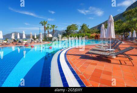 Belle piscine avec chaises longues et parasols au lever du soleil Banque D'Images