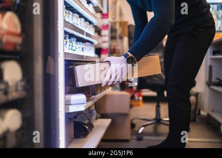 Le propriétaire masculin garde l'emballage dans les tablettes pendant qu'il travaille au magasin Banque D'Images