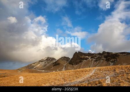 Paysage islandais typique de sommets de montagne volcanique et collines vallonnés avec sentiers de randonnée. Scène d'hiver avec un dépoussiérage de neige à Vik, dans le sud de l'I Banque D'Images