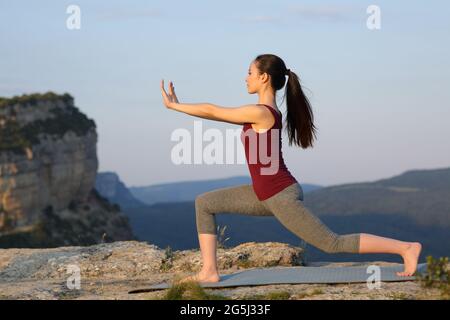 Vue latérale portrait d'une femme asiatique pratiquant l'exercice de tai chi à l'extérieur dans la falaise de montagne Banque D'Images
