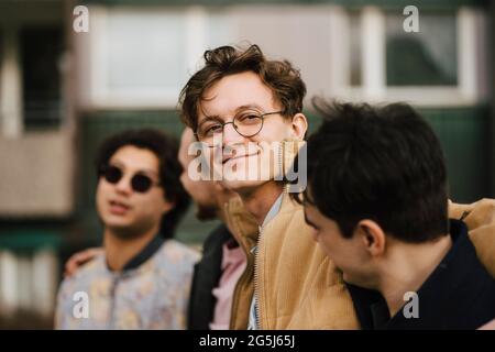 Portrait d'un jeune homme souriant avec des amis masculins Banque D'Images
