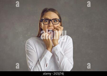 Portrait studio d'une jeune femme effrayée en lunettes qui paniquent et crient bruyamment Banque D'Images