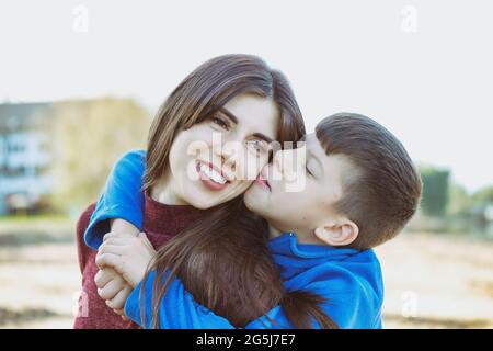 Son câlins maman et s'amuser - son embrasse maman et jouer à l'extérieur - maman et fils ont du plaisir qu'ils sont heureux d'être ensemble Banque D'Images