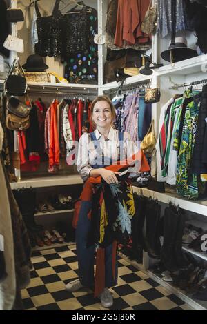 Femme propriétaire debout avec des vêtements dans la boutique Banque D'Images