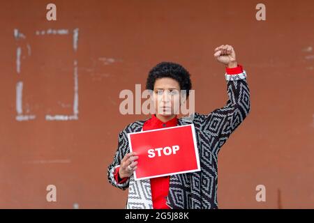 Italie, Toscane, Pistoia, femme tenant le panneau stop et levant le poing Banque D'Images