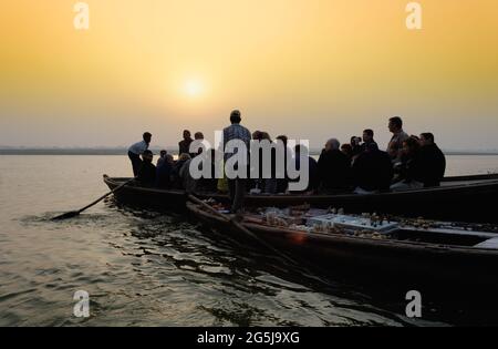 Bateaux tôt le matin et à l'aube de touristes et de vendeurs de souvenirs sur le Gange à Varanasi, Uttar Pradesh, Inde Banque D'Images