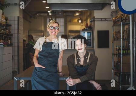 Portrait d'une femme propriétaire debout par un employé dans le magasin Banque D'Images