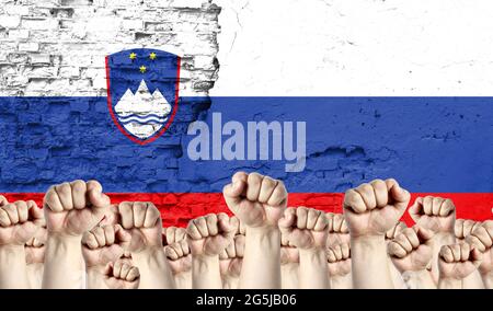 Des poings d'hommes élevés sur le fond du drapeau de la Slovénie peint sur le mur, le concept d'unité populaire et l'opinion de la majorité. Banque D'Images