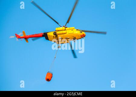 Hélicoptère de feu transportant de l'eau, fond bleu ciel, espace de copie. Banque D'Images