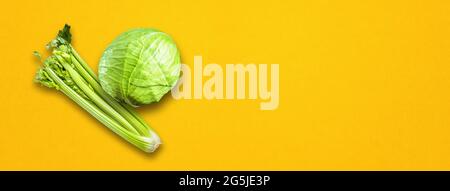 Bouquet de branches de céleri et chou vert isolé sur fond de bannière jaune. Vue de dessus Banque D'Images
