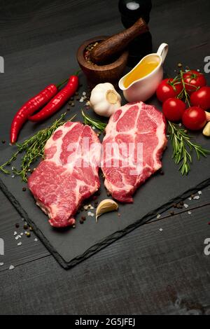 Bœuf frais cru ou steaks de porc sur la planche à découper en pierre Banque D'Images