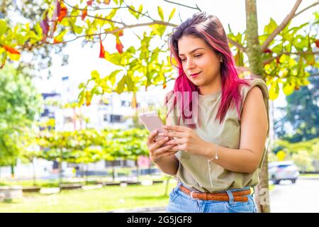 une jeune fille dans le parc discutant depuis son smartphone Banque D'Images