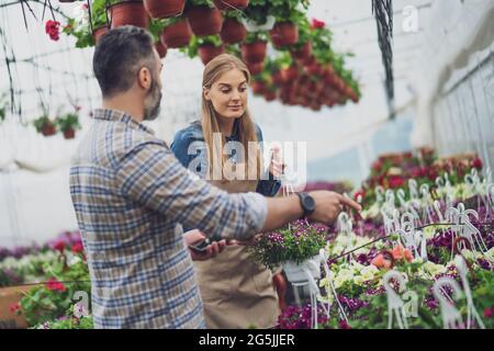 Le couple est propriétaire d'un magasin de serre de petite entreprise. Ils examinent les plantes. Banque D'Images