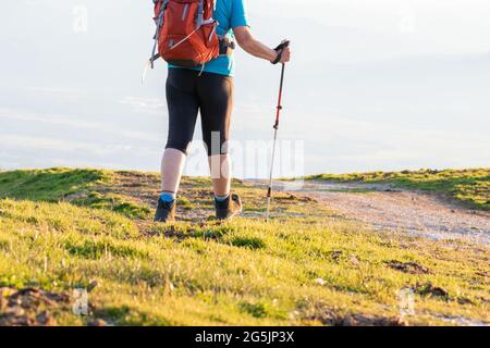 Randonneur avec sac à dos et bâtons de marche sur une montagne au coucher du soleil. Banque D'Images