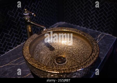 Un joli robinet vintage et un mélangeur doré tapoter sur un lavabo rond en marbre dans la salle de bains. Intérieur d'une toilette chère avec un lavabo en marbre Banque D'Images