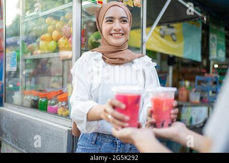 sourire belle fille en voile donne deux tasses de glace de fruit au client Banque D'Images