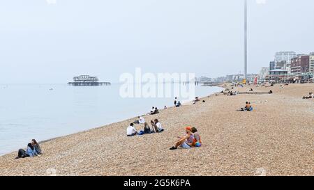 Brighton UK 28 juin 2021 - visiteurs sur la plage de Brighton sur une après-midi chaude mais brumeuse le long de la côte sud : Credit Simon Dack / Alamy Live News Banque D'Images