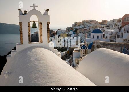 Une cloche d'église surplombe la ville d'Oia et la caldeira sur l'île grecque de Santorin. Banque D'Images