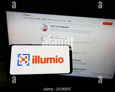 Personne tenant un téléphone portable avec le logo de l'entreprise américaine de sécurité de cloud computing Ilumio Inc. À l'écran devant la page Web. Mise au point sur l'affichage du téléphone. Banque D'Images