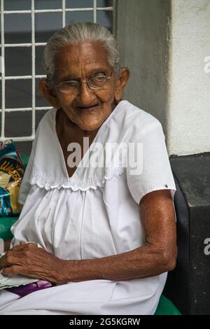 Vieille dame assise à l'extérieur de sa maison, Mumbai, Inde Banque D'Images