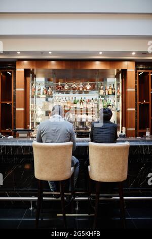 Portrait vertical de deux hommes d'affaires au bar du hall de l'hôtel pendant un voyage d'affaires Banque D'Images