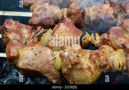 Brochettes de porc accroché à une brochette de métal et faire frire sur le gril Banque D'Images