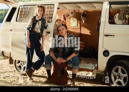 Portrait de jeunes couples debout près de la camionnette et regardant l'appareil photo qu'ils voyagent sur la nature Banque D'Images