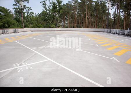 Stationnement sur le toit vide. Les flèches directionnelles de circulation et les places de stationnement sont marquées de peinture blanche et jaune sur l'asphalte. Place de parking sans voitures Banque D'Images