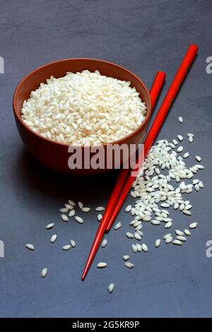 Riz blanc, grains de riz dans un bol avec baguettes Banque D'Images