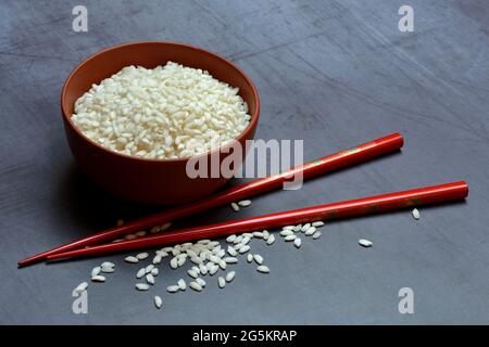 Riz blanc, grains de riz dans un bol avec baguettes Banque D'Images