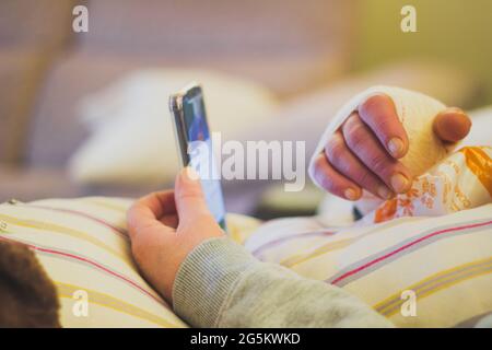 la main de la femme a bandé avec de la glace en regardant le mobile Banque D'Images
