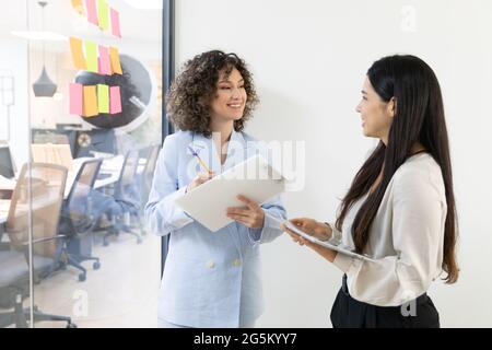 Des femmes d'affaires heureuses qui discutent et font du brainstorming ensemble au bureau. Banque D'Images