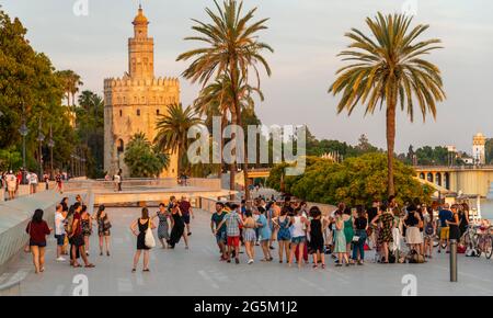 Dansant les gens à la promenade Muelle de la sal, à l'arrière Torre del Oro, lumière du soir, Séville, Andalousie, Espagne, Europe Banque D'Images