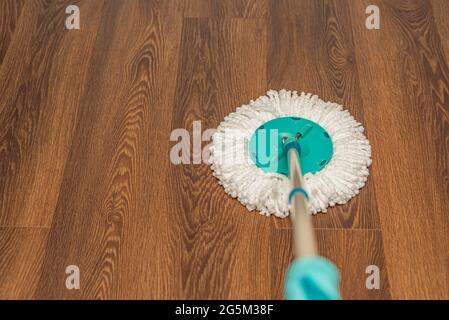 Nettoyage et désinfection des sols, nettoyage à l'eau de la maison. Laver le sol en vinyle brun avec une vadrouille ronde, le nettoyage de la maison, placer pour le texte Banque D'Images