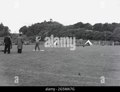 1956, historique, scottish highland games, un candidat dans le jet de marteau, regardé par les officiels en manteaux, pas de kilt exposé. Banque D'Images