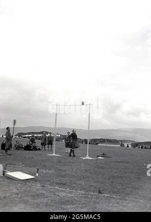 1956, historique, scottish Highland games, Weight Throw, un candidat masculin dans le kilt jetant un poids avec une poignée sur une hauteur définie, un concours traditionnel d'homme fort dans les Highland Games. Banque D'Images