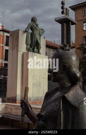 Statue d'une jeune femme sur la place Pilar à Saragosse. Statue de Goya floue en arrière-plan Banque D'Images