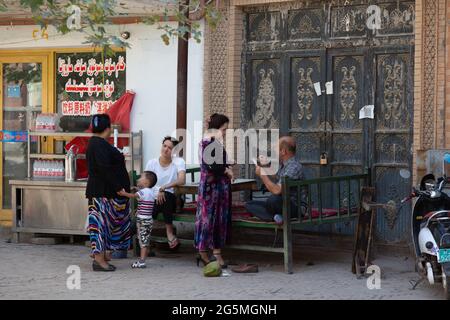 Une famille est assise devant son magasin et parle Banque D'Images