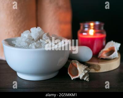 Composition with mortar filled with sea salt, towels, burning candle and sea shells. Spa, massage and beauty treatment concept Banque D'Images