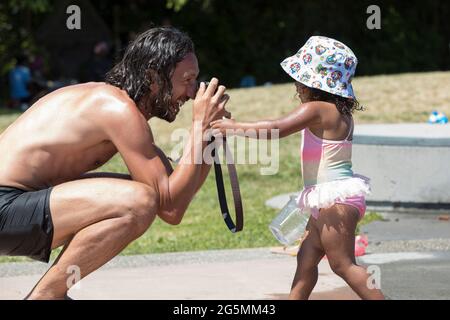 Seattle, Washington, États-Unis. 28 juin 2021. Ruben Molinas Sanchez essaie de prendre une photo de sa fille Max, âgée de 2 ans, tout en se refroidissant dans un parc d'attractions lors d'une vague de chaleur historique à Seattle. Le Nord-Ouest du Pacifique oscillent sous un avertissement de chaleur excessive, brisant les températures records précédentes au cours du week-end avec des températures qui devraient atteindre plus de 110 degrés dans la ville. Crédit : Paul Christian Gordon/Alay Live News Banque D'Images