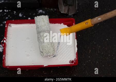 Peinture blanche dans le récipient. Rouleau de peinture pour peindre le mur. Banque D'Images