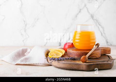 Planches avec un balancier en bois, un pot de miel et de fruits sur fond clair Banque D'Images