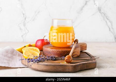 Planches avec un balancier en bois, un pot de miel et de fruits sur fond clair Banque D'Images