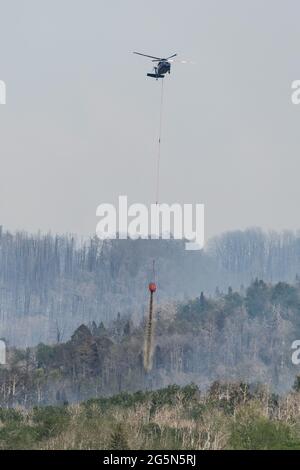 Un hélicoptère Sikorsky CH-60 Blackhawk de lutte contre les incendies laisse tomber de l'eau d'un héliseau sur un feu de forêt dans les montagnes de la Sal, dans l'Utah. Banque D'Images