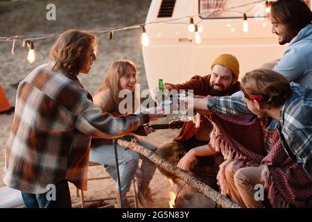 Groupe d'amis assis à l'extérieur et de toaster avec des boissons alcoolisées pendant la fête sur la nature Banque D'Images