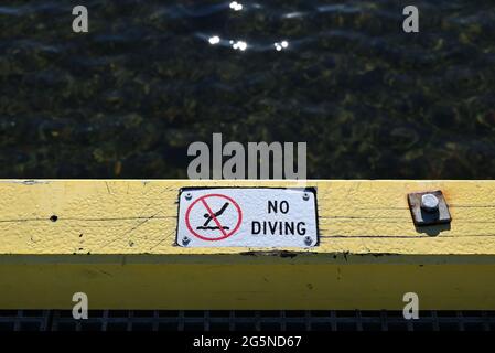 Un panneau humide de non plongée sur un quai ou une jetée, avertissement du danger posé par le fond d'eau peu profond Banque D'Images